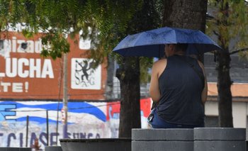 Un hombre sentado en una plaza con un paraguas