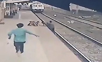 Fragmento del video en el que un hombre rescata a un niño que cae sobre las vías del tren en una estación de India