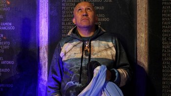 Un hombre sostiene la bandera argentina en el monumento que está en Buenos Aires a los caídos en la guerra