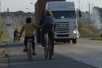 Dos niños circulan en bicicleta sobre la banquina de la Ruta 8, en el lugar del accidente.