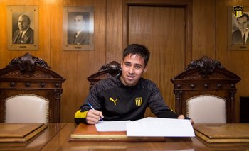 Óscar Cruz firmando contrato profesional en la sede de Peñarol