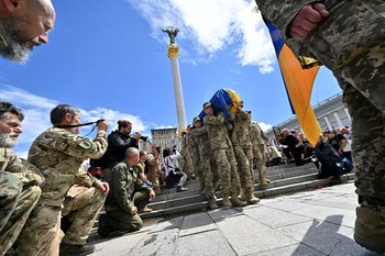 Archivo, 22 de junio: Soldados ucranianos se arrodillan mientras otros camaradas cargan el cajón del fallecido comandante Oleh Kutsyn