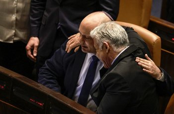 El canciller Yair Lapid, a la derecha, se abraza al saliente primer ministro Naftali Bennett, a la izquierda; tras la disolución del Parlamento en Jerusalem este jueves 30