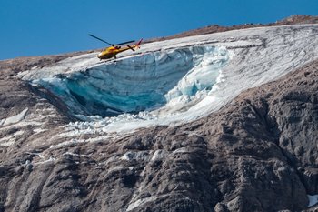 Un helicóptero vuela sobre el glaciar que se derrumbó el domingo en la montaña de la Marmolada