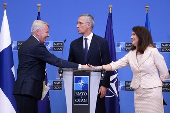 Los ministros de Relaciones Exteriores de Finlandia y Suecia, Pekka Haavisto y Anne Linde, respectivamente, se dan la mano; el secretario general de la OTAN, Jens Stoltenberg, está en el medio
