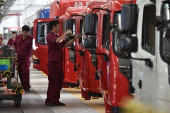 Empleados de una empresa en Fuyang, China, trabajan con camiones 