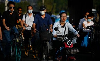 Ciudadanos chinos viajan en bicicleta y moto en Beijing, China. Archivo
