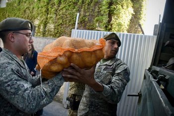 Dos efectivos cargan una bolsa de papas a un camión del Ejército