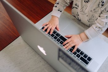 Niño tocando el teclado de una computadora Apple