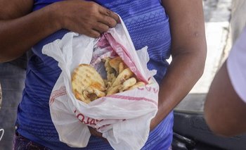 Una mujer muestra unos panes recién encontrados en un camión de basura