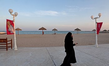 Una mujer camina frente a una playa en Doha