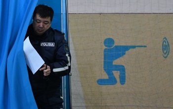 Un oficial de policía vota en una mesa de votación en el gimnasio de una escuela durante las elecciones presidenciales de Kazajstán