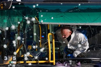 Un médico forense estudia la escena del crimen tras la explosión de una bomba en una parada de ómnibus