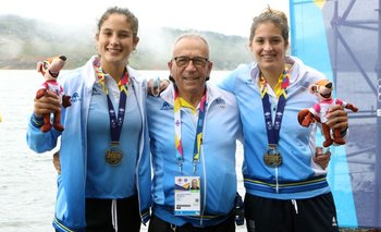 Yuliana Etchevarne, Zoe Acosta y el entrenador Osvaldo Borchi con la medalla de oro