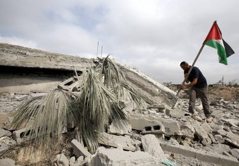 Un hombre coloca una bandera palestina en los escombros del hogar de un prisionero que fue destruido con explosivos