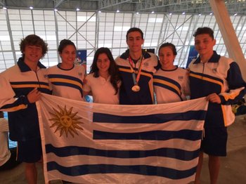 Santiago Saint-Upery con su medalla y junto a los demás integrantes del equipo de natación