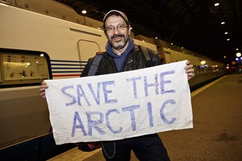 El activista de Greenpeace Dmitri Litvinov muestra un cartel que dice "Salva al Ártico", al llegar a la estación de tren en Hlesinki, el jueves